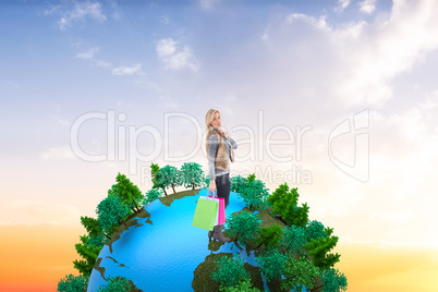 Composite image of blonde in winter clothes holding shopping bag