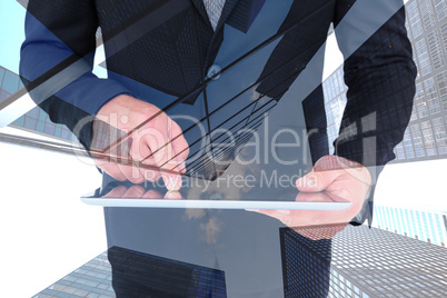 Composite image of businessman using his tablet pc