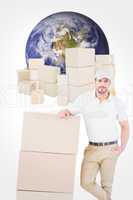 Composite image of confident delivery man leaning on cardboard b