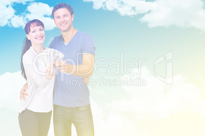 Composite image of couple holding fan of cash