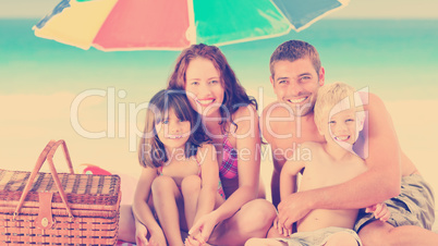 Family posing under a beach umbrella on the beach