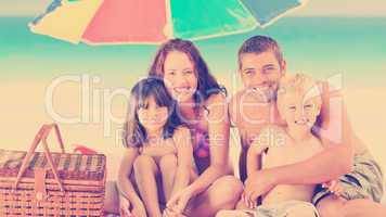 Family posing under a beach umbrella on the beach