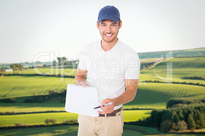 Composite image of happy delivery man holding clipboard