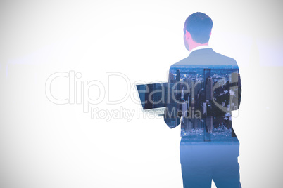 Composite image of businessman looking up holding laptop
