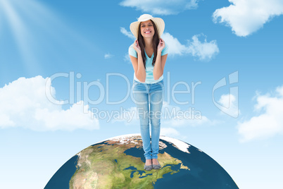 Composite image of happy young brunette wearing sunhat