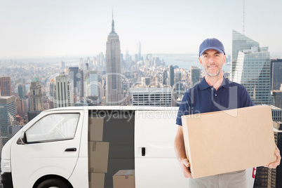 Composite image of happy delivery man holding cardboard box