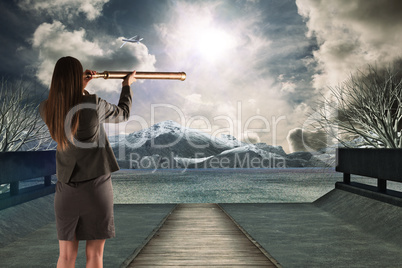 Composite image of businesswoman looking through a telescope