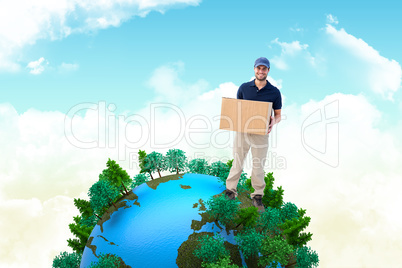 Composite image of happy delivery man holding cardboard box