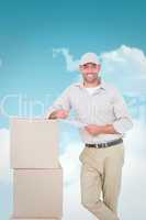 Composite image of delivery man with clipboard leaning on cardbo