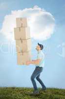 Composite image of shocked delivery man carrying stack of boxes