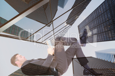 Composite image of businessman lying on the floor reading book