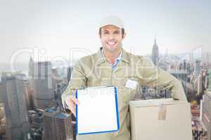 Composite image of happy delivery man with box showing clipboard