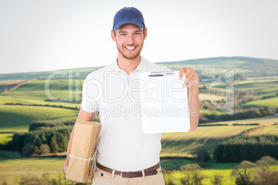 Composite image of happy delivery man holding cardboard box and