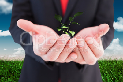 Composite image of businessman presenting with his hands