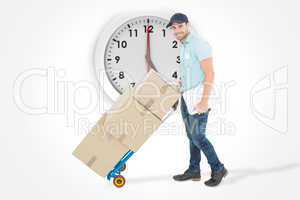 Composite image of confident delivery man pushing trolley of box