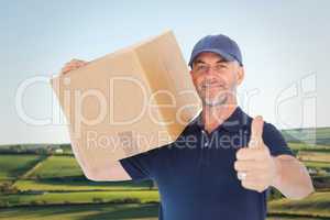 Composite image of happy delivery man holding cardboard box show