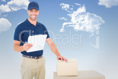 Composite image of happy delivery man with cardboard boxes and c