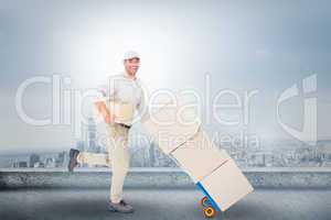 Composite image of happy delivery man with trolley of boxes runn