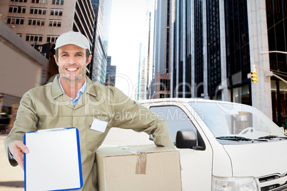 Composite image of happy delivery man with box showing clipboard