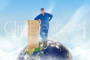 Composite image of happy delivery man leaning on pile of cardboa