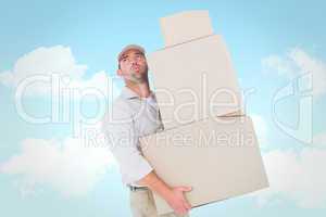 Composite image of tired delivery man carrying stack boxes