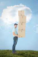 Composite image of confident delivery man carrying stack of boxe