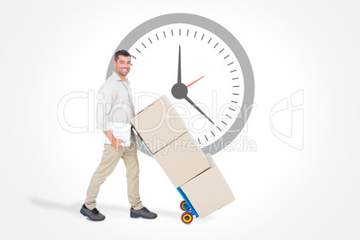 Composite image of happy delivery man pushing trolley of boxes