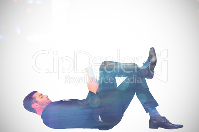 Composite image of businessman lying on the floor reading book