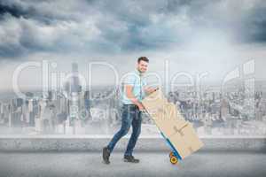 Composite image of happy delivery man pushing trolley of boxes