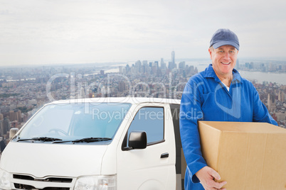 Composite image of happy delivery man holding cardboard box