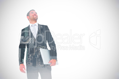 Composite image of businessman looking up holding laptop