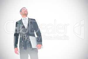 Composite image of businessman looking up holding laptop