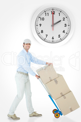 Composite image of happy delivery man pushing trolley of cardboa