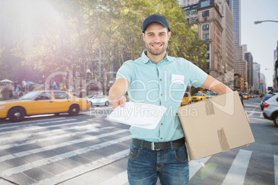Composite image of delivery man with package giving clipboard fo