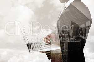 Composite image of businessman holding laptop