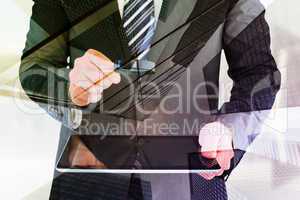 Composite image of businessman looking at tablet with magnifying