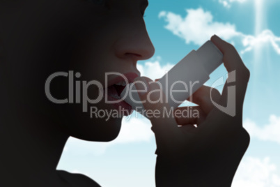 Composite image of blonde woman taking her inhaler Composite image of blonde woman taking her inhaler