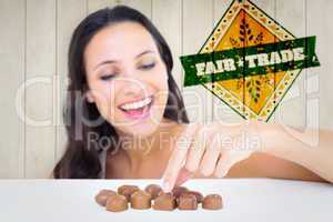 Composite image of pretty brunette picking out chocolate