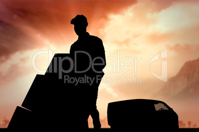 Composite image of happy delivery man pushing trolley of boxes