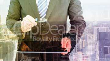 Composite image of businessman looking at tablet with magnifying