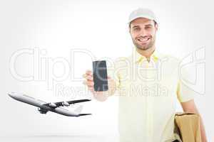 Composite image of handsome delivery man showing mobile phone