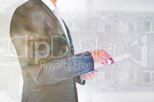 Composite image of businessman using his tablet pc