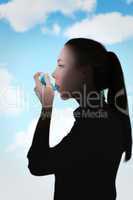 Composite image of beautiful blonde using an asthma inhaler