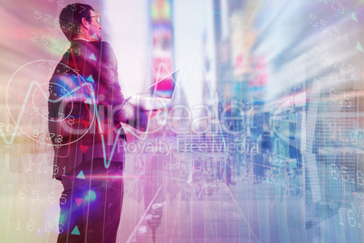 Composite image of businessman looking up holding laptop