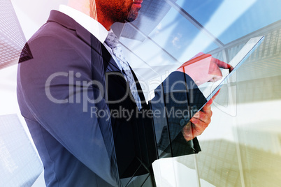 Composite image of businessman using his tablet pc