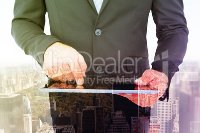 Composite image of businessman using his tablet pc