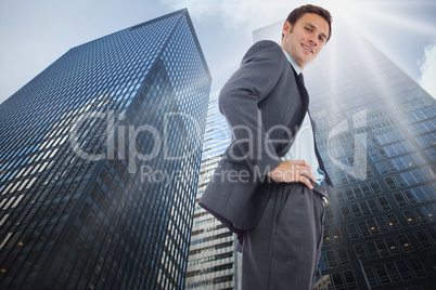 Composite image of cheerful businessman standing with hands on h