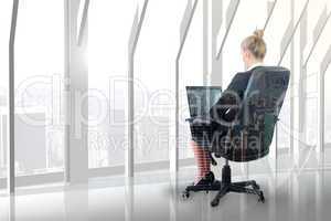 Composite image of businesswoman sitting on swivel chair with la