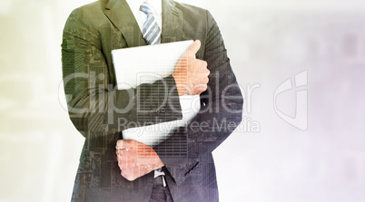 Composite image of businessman holding his laptop tightly