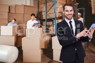 Composite image of businessman using his tablet while looking at